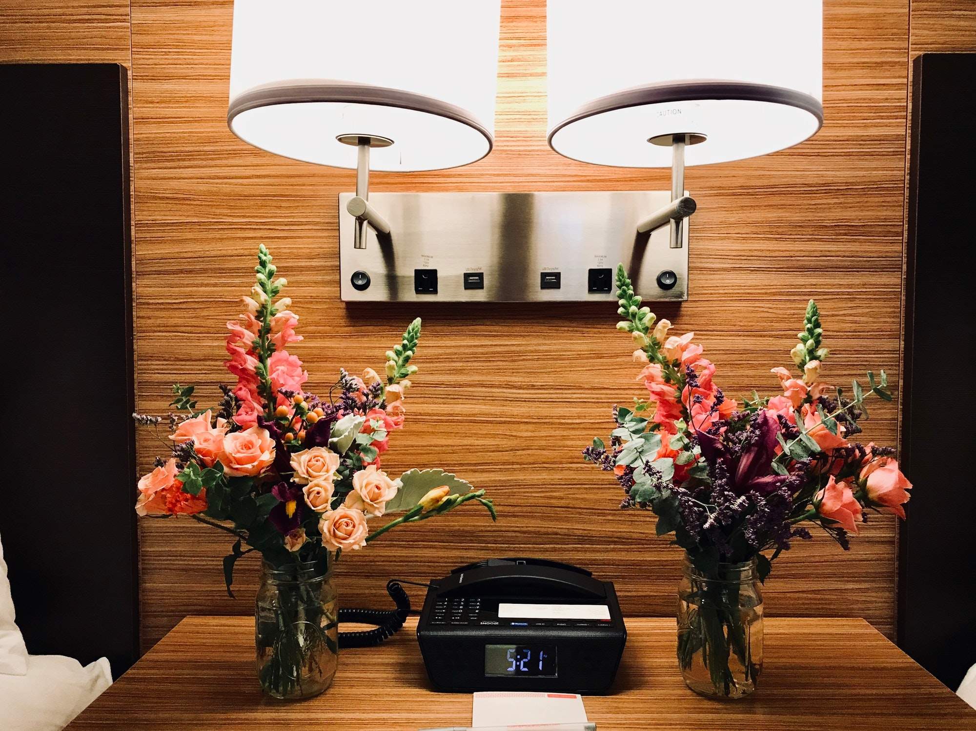 nightstand-in-a-hotel-room-with-flowers-telephone-clock-and-lamps.jpg